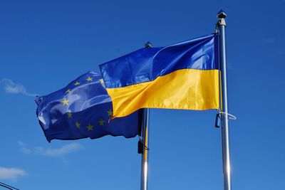 Low angle view of ukrainian and european union flags against blue sky