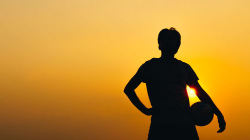 Silhouette man standing against orange sky