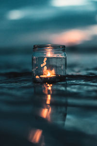 Lit tea light in jar on table