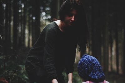 Mother standing with daughter against trees in forest