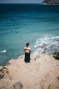 Rear view of man standing on rock at beach