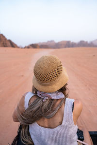 Rear view of woman wearing hat standing on field against sky