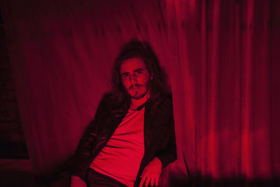 Mid adult man sitting on red wall