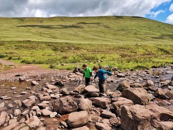 Rear view of people walking on rocks against sky