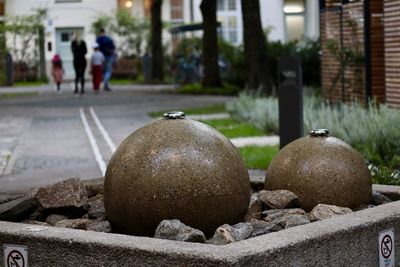 Close-up of stones on footpath by street against buildings