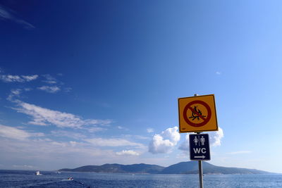 Information sign by road against sky