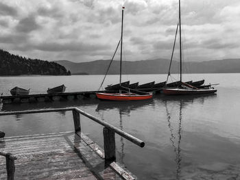 Sailboats moored in lake against sky