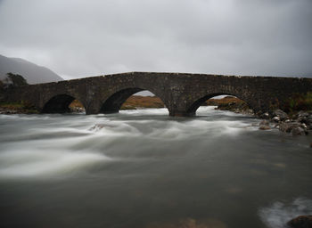 Arch bridge over river against sky