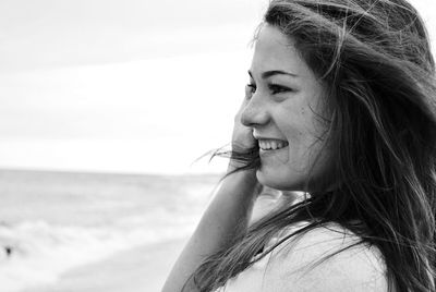 Close-up of happy young woman at beach against sky