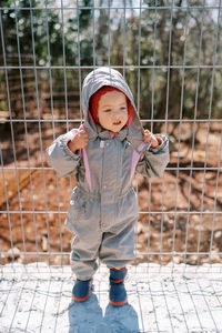 Portrait of cute girl standing against fence