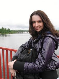 Portrait of smiling young woman sitting against river