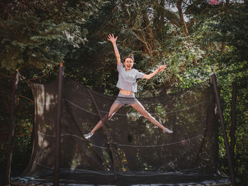 A beautiful slender caucasian teenage girl in shorts and a blouse jumps on a trampoline