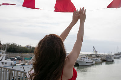 Rear view of woman holding bunting flag hanging at harbor