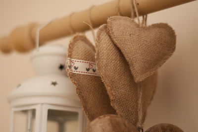Close-up of jute hearts and lantern hanging on rod against wall