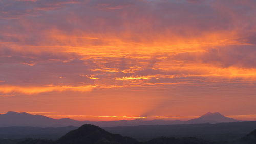 Scenic view of silhouette mountains against orange sky