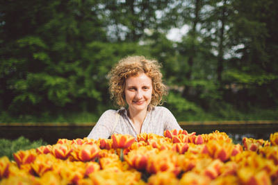 Portrait of woman with orange flowers against trees