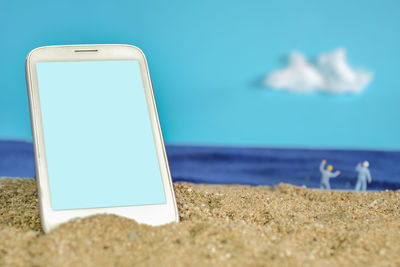 Close-up of mobile phone on beach