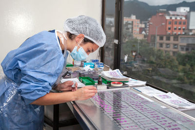 Young female scientist preparing slides with paraffin-embedded sections for pathological analysis .