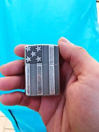 Cropped hand of man holding american flag cigarette lighter