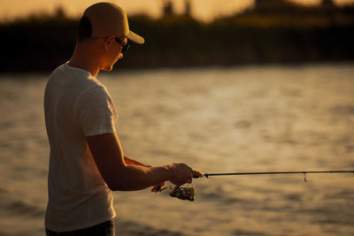 Rear view of man standing by lake