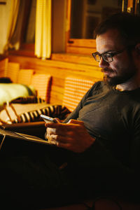 Mid adult man using mobile phone while sitting at home