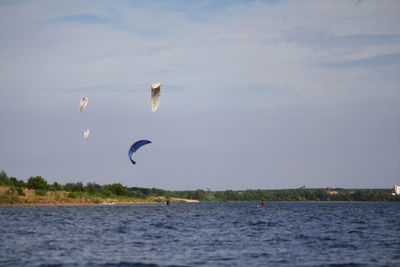 Person kiteboarding in sea against cloudy sky