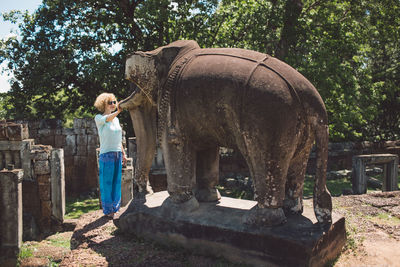 Woman looking at elephant statue against trees