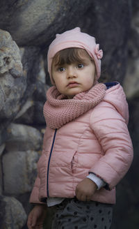 Girl wearing jacket looking away against rock