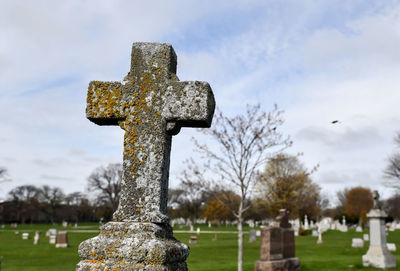 Cross in cemetery against sky