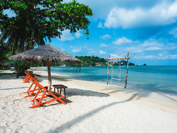 Scenic view of koh mak island beach chair and thatched roof umbrella on white sand beach. thailand