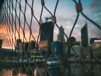 Close-up of chainlink fence against sky during sunset