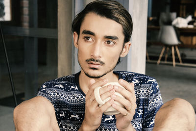 Man looking away while having coffee in cafe