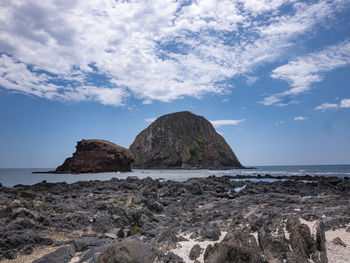 Rock formation on beach against sky