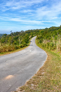 Empty road along countryside landscape against sky