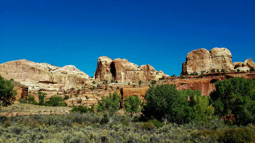 Rock formations on river trail against clear blue sky