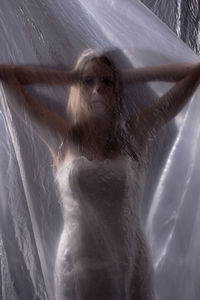 Portrait of young woman behind curtain