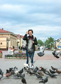 Side view of woman sitting on street against sky