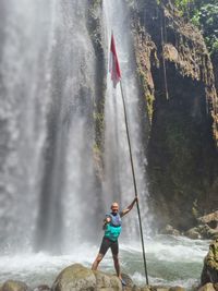 Low angle view of man standing front of waterfall