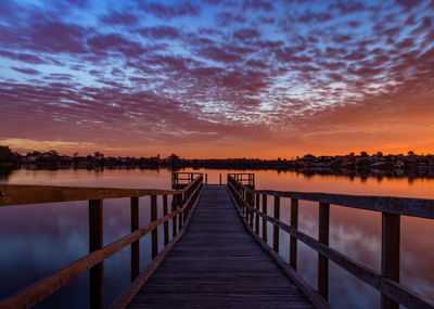 Pier over lake against sky during sunset