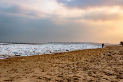 Man standing on beach against sky during sunset