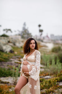 Young pregnant woman posing at beach in sheer dress