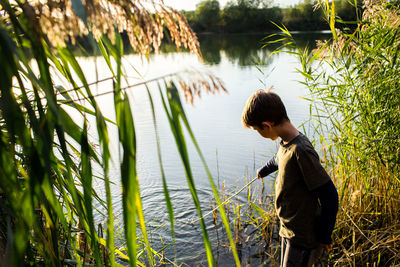 Side view of man standing by lake