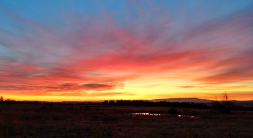 Scenic view of dramatic sky over land during sunset