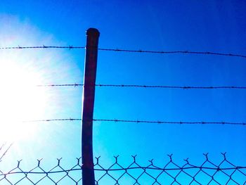 Low angle view of barbed wire against blue sky