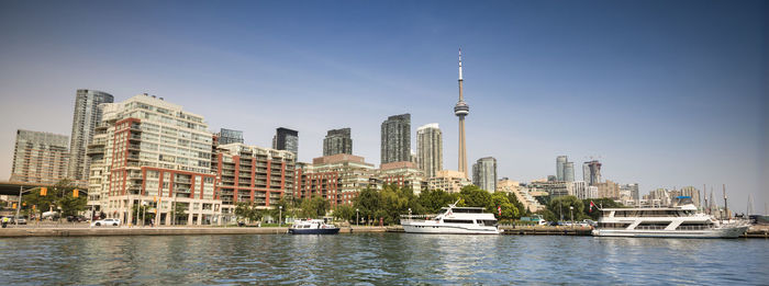 Modern buildings by river against sky in city