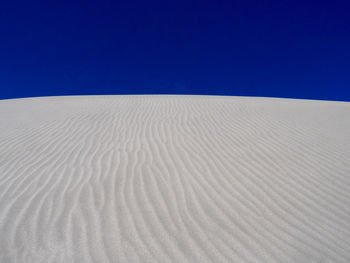 Sand dunes in desert against clear blue sky