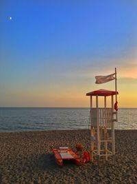 Lifeguard hut on beach against sky during sunset