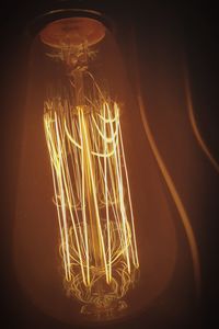 Low angle view of illuminated light bulb against black background