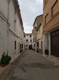 Empty road amidst buildings against sky