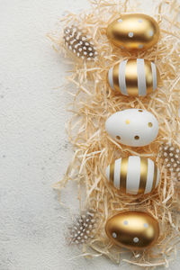Easter eggs painted with gold paint on a straw background. 
